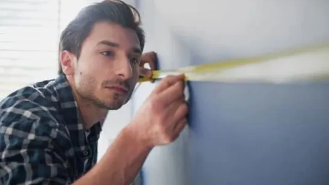 페인트 계산을 위해 줄자로 벽 가로 길이를 측정하는 모습