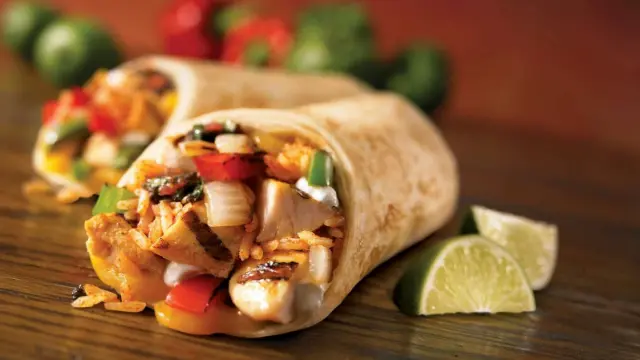 Two wraps filled with chicken and vegetables, served with lime wedges