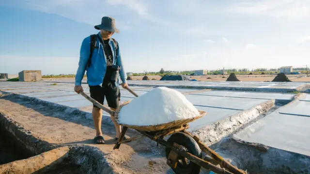 A person carrying salt at a salt farm