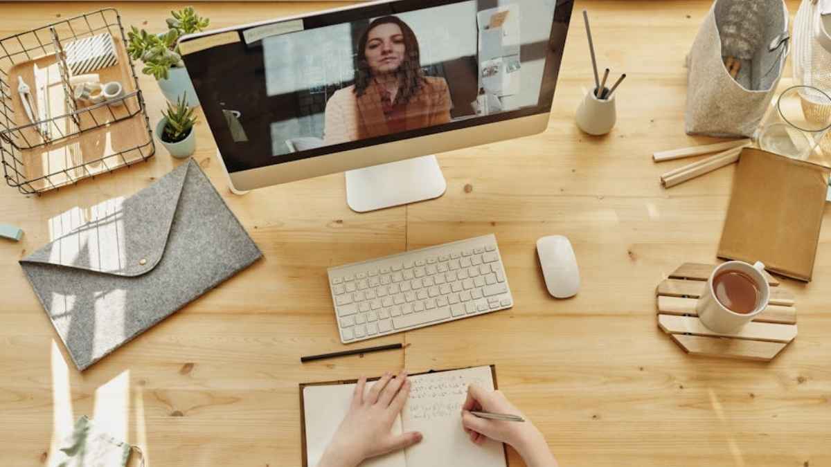 A student desk with a monitor, a notebook, and a cup of coffee
