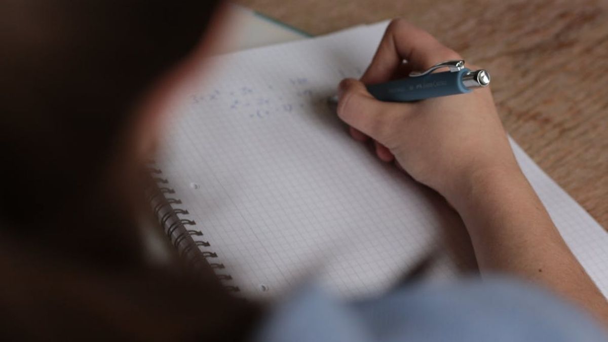 Female student writing math formulas in a notebook